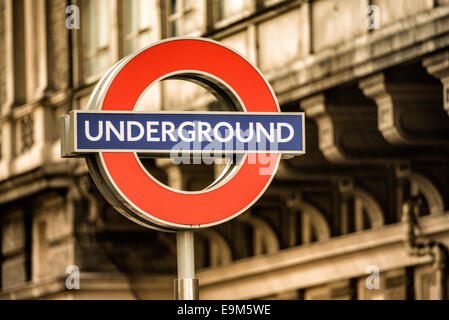 LONDON, Großbritannien – das berühmte Londoner U-Bahn-Schild mit einem roten Kreis und einer blauen Leiste markiert den Eingang zu einer U-Bahn-Station. Dieses Symbol, das als „Roundel“ bekannt ist, ist ein weithin anerkanntes Wahrzeichen des öffentlichen Verkehrssystems von London. Die Londoner U-Bahn, allgemein bekannt als die U-Bahn, ist eines der ältesten und umfangreichsten U-Bahn-Netze der Welt. Stockfoto