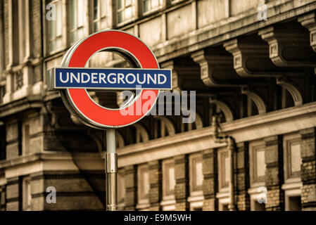 LONDON, Großbritannien – die berühmte U-Bahn-Station mit einem roten Kreis und einer blauen Bar markiert den Eingang zu einer U-Bahn-Station. Das Symbol ist seit 1908 ein Teil der visuellen Identität Londons und entwickelte sich von früheren Designs zu einem der weltweit bekanntesten Verkehrssymbole. Die Londoner U-Bahn, allgemein bekannt als die U-Bahn, eröffnete ihre erste Linie im Jahr 1863 und ist eines der ältesten und umfangreichsten U-Bahn-Netze der Welt. Transport for London unterhält dieses Netz, das täglich Millionen von Passagieren über mehr als 270 Bahnhöfe bedient. Stockfoto