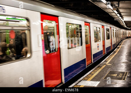 LONDON, Großbritannien – Ein U-Bahn-Zug fährt von einer U-Bahn-Haltestelle aus und fährt vom Bahnsteig des berühmten Londoner U-Bahn-Systems ab. Die Londoner U-Bahn, ein wichtiger Teil des öffentlichen Verkehrsnetzes der Stadt, bedient täglich Millionen von Fahrgästen im Großraum London. Stockfoto