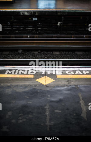 LONDON, UK-gemalten Schildern auf einer Londoner U-Plattform Warnung Passagiere die Lücke zwischen Zug und Bahnsteig beim Betreten und Verlassen des Zuges zu kümmern. Stockfoto