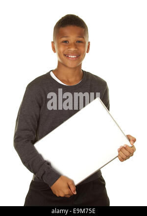 Hübsche elfjährige African American Boy Holding einen Laptop-Computer und lächelnd auf weißem Grund Stockfoto