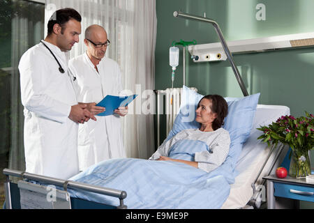 Zwei Ärzte neben einer Patientin in einer Krankenstation Stockfoto