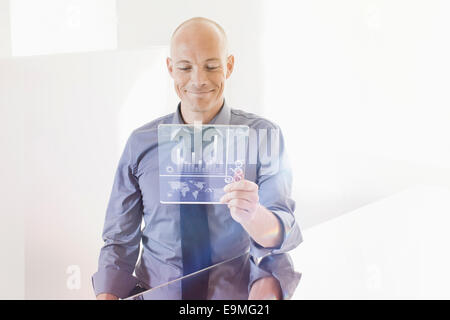 Lächelnd Geschäftsmann Blick auf futuristische digital-Tablette am Schreibtisch im Büro Stockfoto