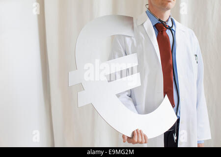 Mittelteil des männlichen Arzt hält Euro-Symbol in Klinik Stockfoto