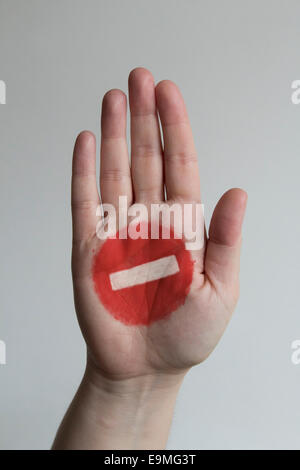 Nahaufnahme des Stop-Schild auf die Hand des Mannes vor grauem Hintergrund gemalt Stockfoto