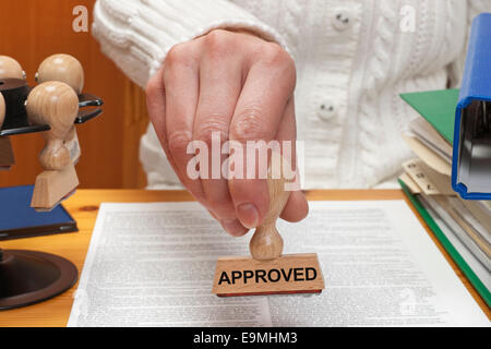 Ein Stempel mit der Aufschrift genehmigt wird in der Hand gehalten. Stockfoto