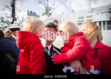 Chief Petty Officer Stuart Davidson erhält Küsse von Töchtern Alice, 4, und Lucy, 18 Monate, wie Frau Lise blickt auf Stockfoto