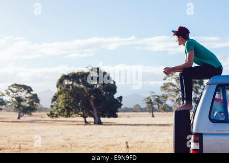 Junger Mann sitzt auf dem Auto, Grampians Nature Reserve, Australien Stockfoto