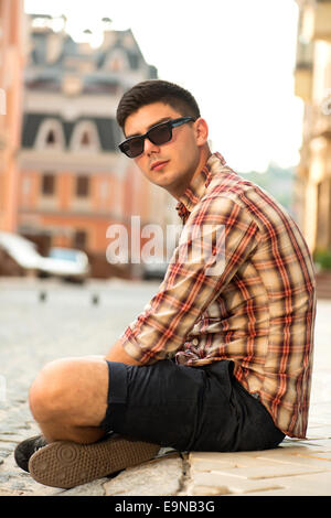 Schönen jungen Mann auf der Straße sitzen Stockfoto