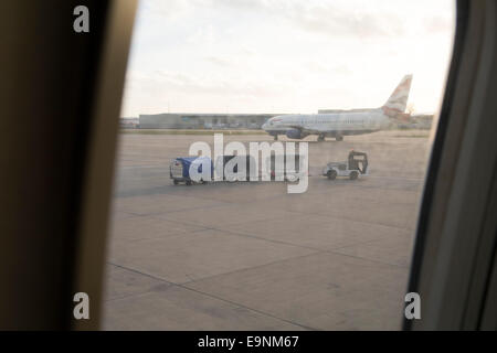 Blick aus einem Flugzeug Fenster oder Gepäck Zug, Gepäckwagen und Flugzeug auf dem Rollfeld Stockfoto