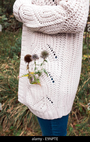 Frau in Wolle Kleidung mit Distel in ihrer Tasche Stockfoto