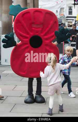 London, UK. 30. Oktober 2014. Kinder werden von einer Frau in einem großen Mohn Kostüm begrüßt. London Poppy Day Feierlichkeiten in Covent Garden in London. Bildnachweis: Nick Savage/Alamy Live-Nachrichten Stockfoto