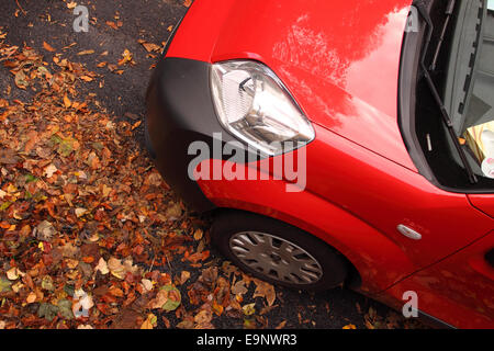 Herbst Autofahren ein rotes Auto, umgeben von Herbstlaub Stockfoto