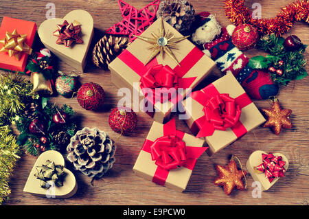 ein Haufen Geschenke und Weihnachtsschmuck, wie Weihnachtskugeln, Sterne und Lametta, auf einem rustikalen Holztisch Stockfoto