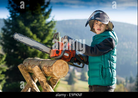 Junge von zehn mit Kettensäge schneiden log Stockfoto