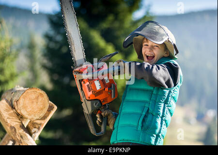 Junge von zehn mit Kettensäge schneiden log Stockfoto