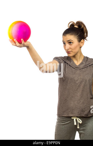 junge Frau, die auf einen bunten Ball auf weißem Hintergrund Stockfoto