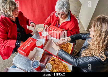 Drei Generationen von Frauen, die bereit waren, Fisch und Chips zu essen, an einem Tisch sitzen, außerhalb Harry Ramsdens neben Strand von Bournemouth, Dorset, England, UK. Stockfoto