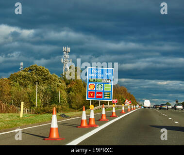 Fleet Services Ausfahrt und fahren Sie auf der Autobahn M4 in Hampshire, im warmen Sonnenschein am frühen Abend. Kegel die Auskleidung der Pannenstreifen. England, UK. Stockfoto