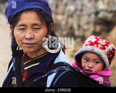 Hmong Frau tragen traditionelle Kleidung und Schmuck mit einem unbekannten Kind Kind in Sapa Stadt, Nord-Vietnam. Stockfoto