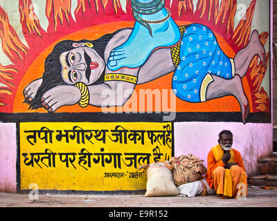 Indischer Mann sitzt vor bunten Streetart Wandbild in Varanasi, Uttar Pradesh, Indien. Stockfoto