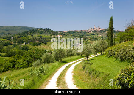 San Gimignano, Toskana, Italien. Blick entlang der gewundenen Feldweg in die entfernten mittelalterlichen Hügel-Stadt. Stockfoto