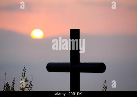 Rocca Ripesena, Umbrien, Italien. Klippe Gedenkstätte Kreuz Silhouette gegen die aufgehende Sonne. Stockfoto