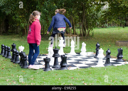 Kinder spielen auf einem Riesen Garten-Schach-Satz Stockfoto