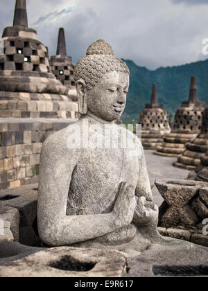 Eine antike Buddhastatue umgeben von Stupas in Borobudur, der weltweit größte buddhistische Monument, Java, Indonesien. Stockfoto