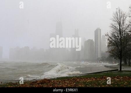 Chicago, Illinois, USA. 31. Oktober 2014. Eine Bö Schnee während der heutigen Gale verdeckt die Gebäude der Innenstadt von Chicago, wie eine große Welle in der Ufermauer stürzt. Orkanartigen Winden produziert Wellen von über 20 Fuß gemessen an einer NOAA Wetter Boje weit heraus auf dem Lake Michigan. Bildnachweis: Todd Bannor/Alamy Live-Nachrichten Stockfoto