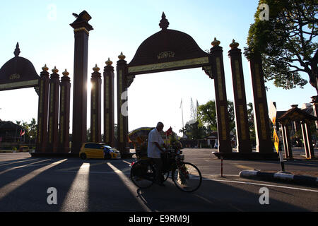 Ein Rikscha-Fahrer geht vor dem Tor ist das Wahrzeichen in Kota Bharu, Kelantan. Stockfoto