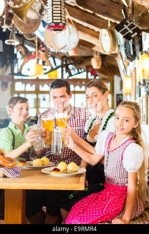 Bayerische Mädchen tragen Dirndl und Essen mit der Familie im traditionellen restaurant Stockfoto