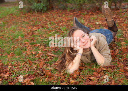 Junge süße Mädchen auf Laub im herbstlichen Wald liegen. Stockfoto