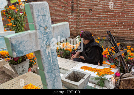 Eine Frau schmückt ein Familienmitglieder Grab am Xoxocatian Friedhof, dekoriert mit Blumen und Kerzen für den Tag der Toten Festival bekannt in Spanisch als D'a de Muertos am 31. Oktober 2014 in Oaxaca, Mexiko. Stockfoto