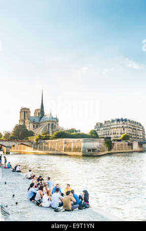 junge Leute haben ein Picknick in den frühen Abendstunden an den Ufern der Seine, im Hintergrund Ile De La cité Stockfoto