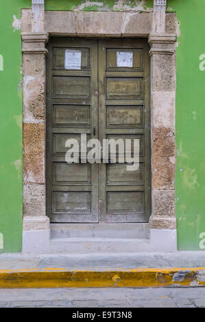 Nahaufnahme eines großen braunen Holztür mit Stein Türverkleidungen auf einem grünen Stuck spanische Haus im Kolonialstil, Campeche, Mexiko Stockfoto