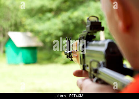 Mann auf eine Zielscheibe Zielen und schießen ein automatisches Gewehr für weichen. Konzentrieren Sie sich auf die Zielfernrohre. Stockfoto