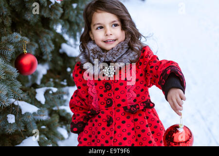 Kleines Mädchen schmücken Weihnachtsbaum außerhalb Stockfoto