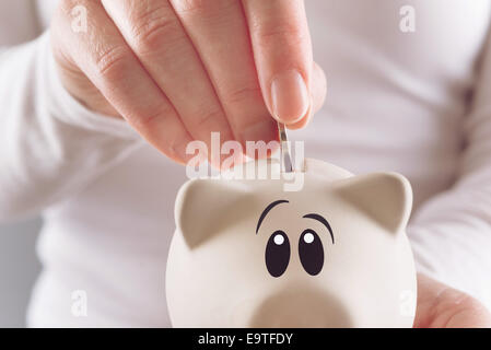 Frau, Münze in Piggy Spardose, selektiven Fokus mit geringen Schärfentiefe Stockfoto