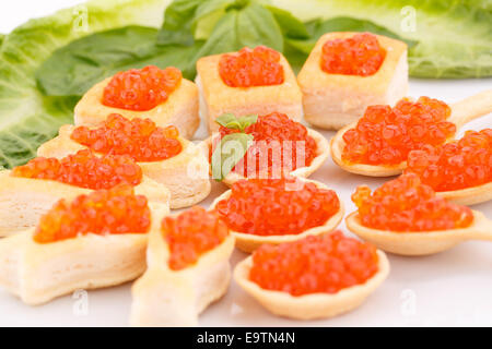 Roter Kaviar in Gebäck und Salat auf Teller. Stockfoto