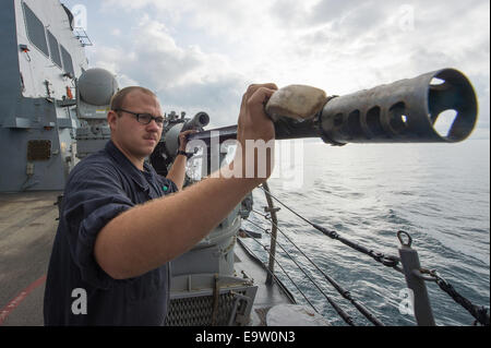 US Marine Gunner Mate Seemann James Lumbley führt periodische Wartungsarbeiten auf der Backbordseite Mark 38 Mod 2 25 mm Maschinengewehr an Bord der Lenkwaffenzerstörer USS Cole (DDG-67) 15. Oktober 2014, im Schwarzen Meer. Das Schiff führte Marinebetriebe Stockfoto