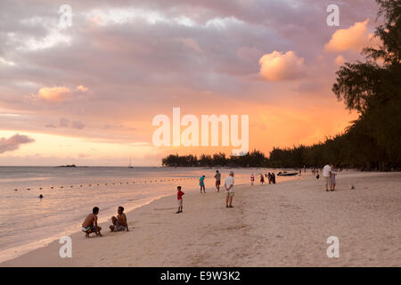 Einheimische und Touristen zu Fuß auf einem tropischen Strand bei Sonnenuntergang, Trou aux Biches, Mont Choisy Beach, North Mauritius Stockfoto