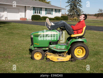 20er Jahre Mann sitzt auf einem Rasentraktor John Deere GX255 Stockfoto