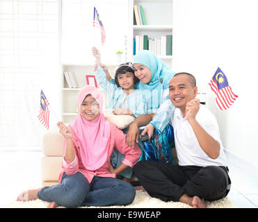 malaysische Familie feiert beim Fernsehen über ein Turnier, tragen einige Länderflaggen Stockfoto