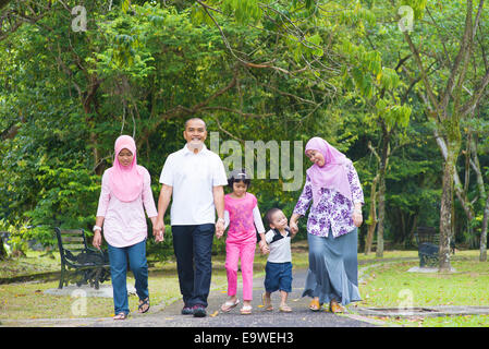 Asiatischen Familie Hand in Hand zusammen auf Gartenweg gehen. Glücklich südostasiatischen outdoor-Lifestyle. Stockfoto