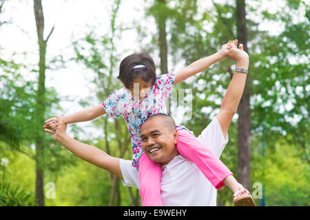 Vater und Tochter spielen Schweinchen zurück auf Outdoor-Garten-Park. Glücklich südostasiatischen Familie leben Lebensstil. Stockfoto