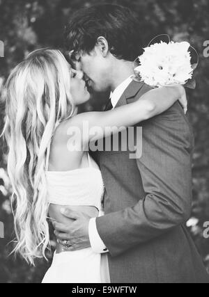 Hochzeit, schöne romantische Braut und Bräutigam küssen und umarmen bei Sonnenuntergang. Schwarz / weiß Bild. Stockfoto
