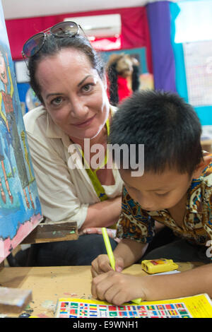 Jakarta, Indonesien. 3. November 2014. Schauspielerin Natalia Woerner malt mit Jason, einem ehemaligen Straßenkind in Jakarta, Indonesien, 3. November 2014. Sie unterstützt die Kindernothilfe, eine deutsche Hilfsorganisation für Kinder, welche ein Kinderdorf in Jakarta wo Kinder einfache Aufgaben Services lernen wie das Waschen und kochen. Laut des indonesischen Ministeriums für soziale Angelegenheiten Leben mehr als 11.000 Kinder auf der Straße in Jakarta. Foto: MAURIZIO GAMBARINI/Dpa/Alamy Live News Stockfoto