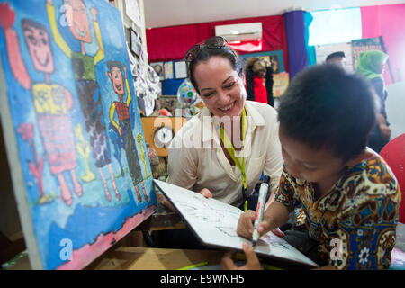 Jakarta, Indonesien. 3. November 2014. Schauspielerin Natalia Woerner malt mit Jason, einem ehemaligen Straßenkind in Jakarta, Indonesien, 3. November 2014. Sie unterstützt die Kindernothilfe, eine deutsche Hilfsorganisation für Kinder, welche ein Kinderdorf in Jakarta wo Kinder einfache Aufgaben Services lernen wie das Waschen und kochen. Laut des indonesischen Ministeriums für soziale Angelegenheiten Leben mehr als 11.000 Kinder auf der Straße in Jakarta. Foto: MAURIZIO GAMBARINI/Dpa/Alamy Live News Stockfoto