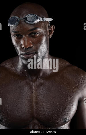 Ermittelten Schwimmer mit nassen Körper, Blick in die Kamera. Porträt des jungen afro-amerikanischen Sportler mit muskulösen Körper.
